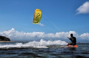 Experience the thrill of kiteboarding on the ocean with waves and vibrant skies.
