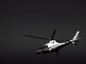 A striking black and white image of a helicopter flying in a clear sky, showcasing its sleek design.