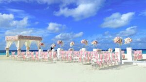 Beautiful beach wedding setup with floral decorations under a vibrant blue sky on a sunny day.